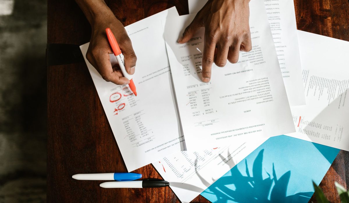 Hands marking up a set of accounts on a desk