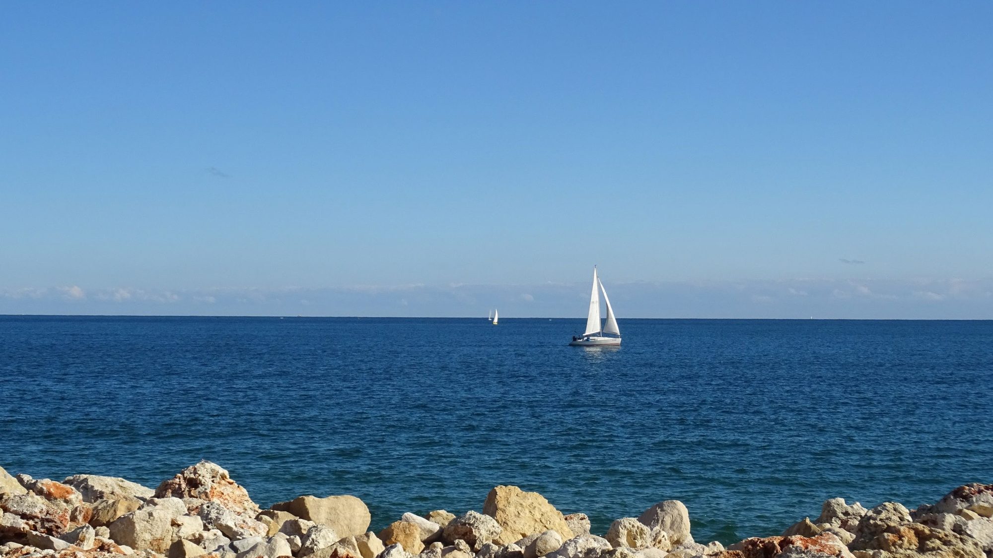 A sailing boat off a rocky shoreline